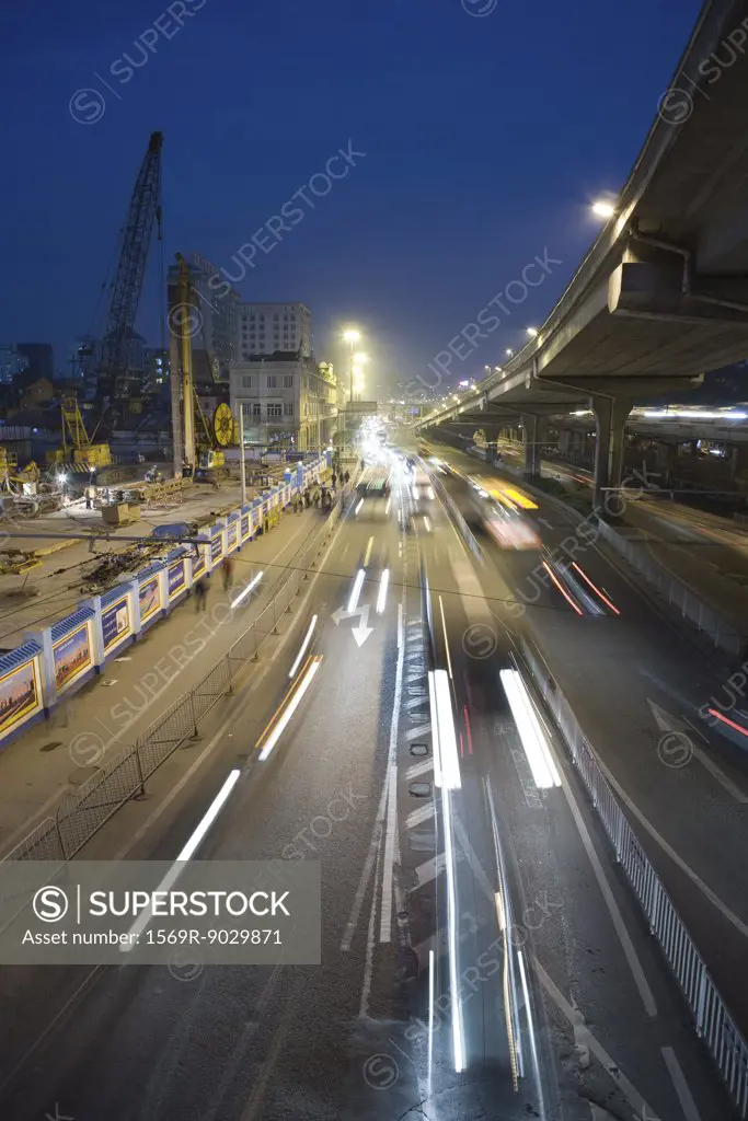 City traffic next to construction site at night, high angle view