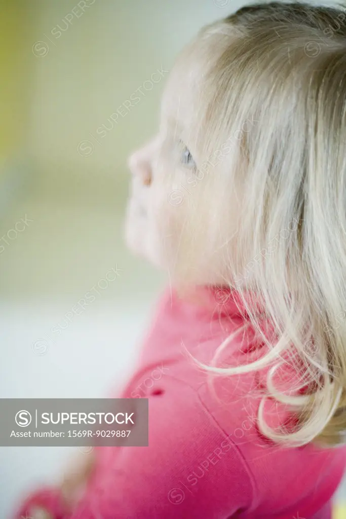 Blonde toddler girl looking up, side view