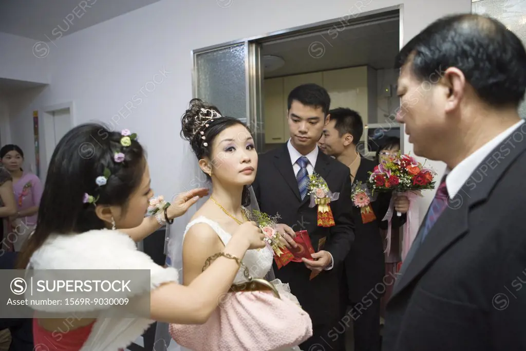 Chinese wedding, bridesmaid putting necklace on bride while others watch