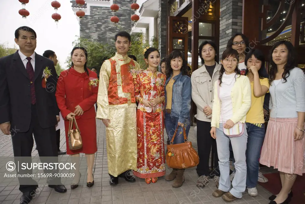 Newlyweds dressed in traditional Chinese clothing, standing with family, group portrait