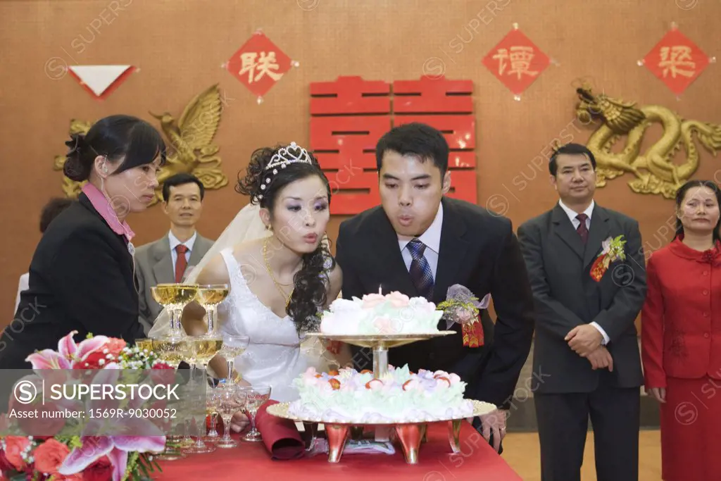 Newlyweds blowing out candle on wedding cake together