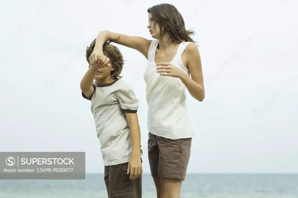Brother and sister at the beach, holding hands, looking at view
