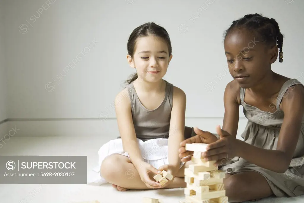 Two girls sitting on floor stacking blocks