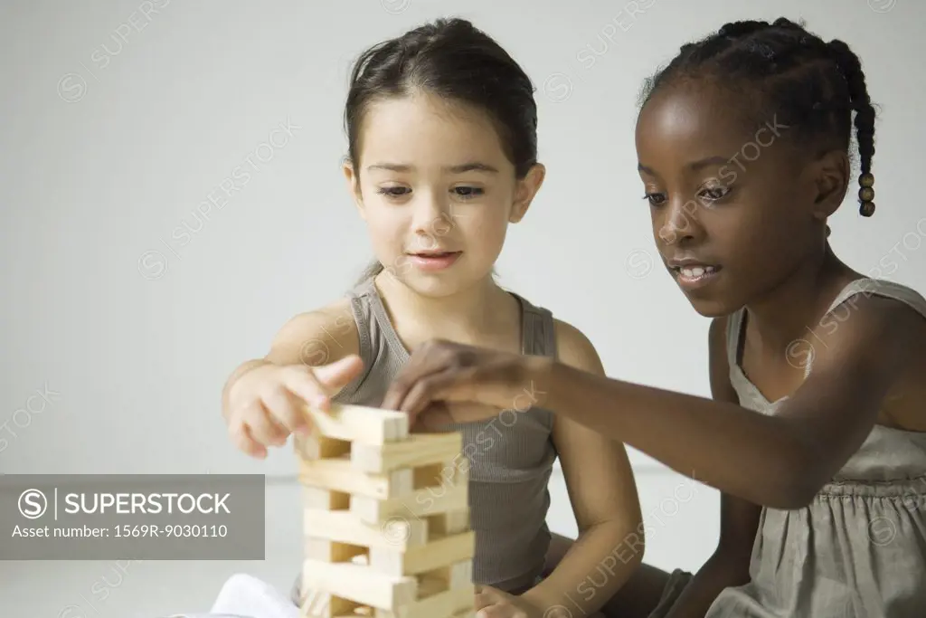 Two girls building tower with blocks together