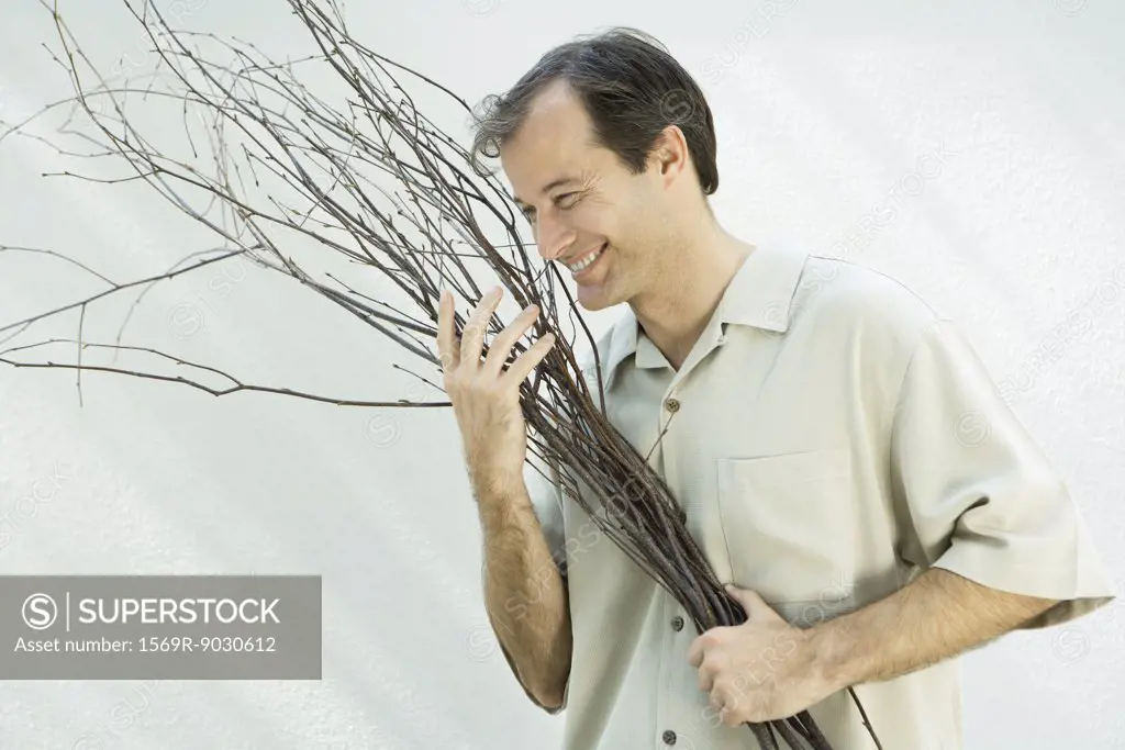Man holding armful of twigs, smiling, looking away