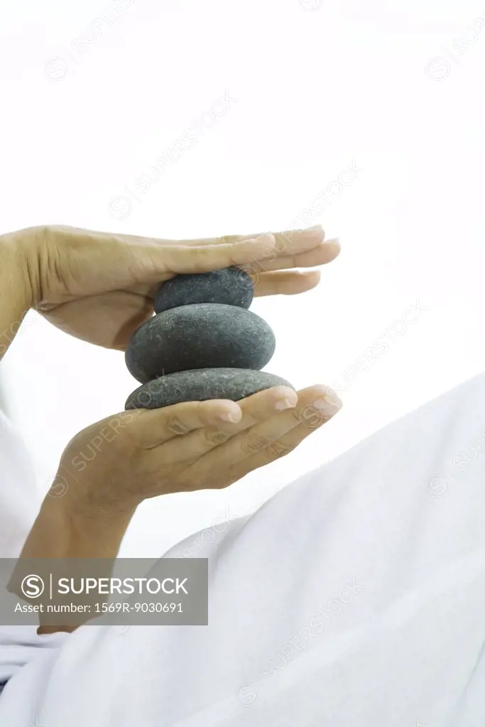 Person holding stacked pebbles in hands, cropped view