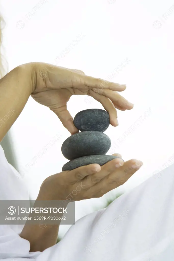 Person stacking pebbles in hand, cropped view