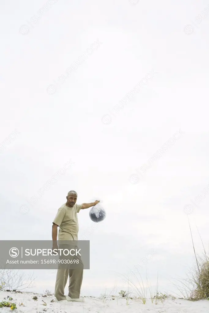 Man holding globe in plastic bag, looking at camera, mid-distance