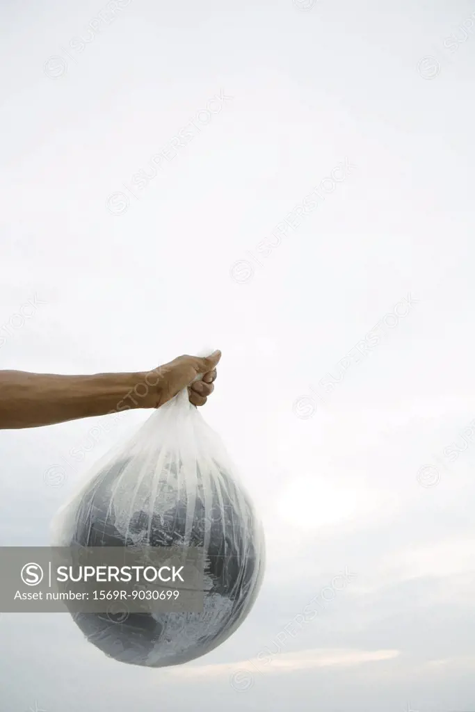 Man holding globe in plastic bag, cropped view