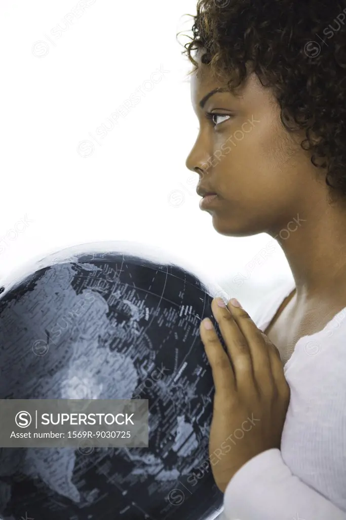 Young woman holding globe, looking away, profile