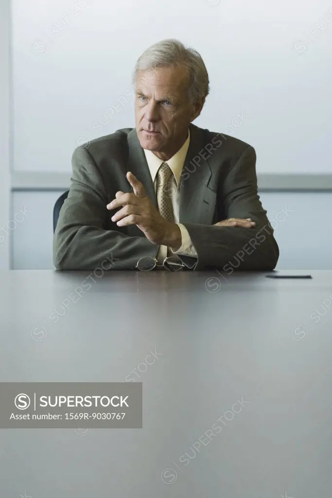 Businessman seated, furrowing brow and pointing finger