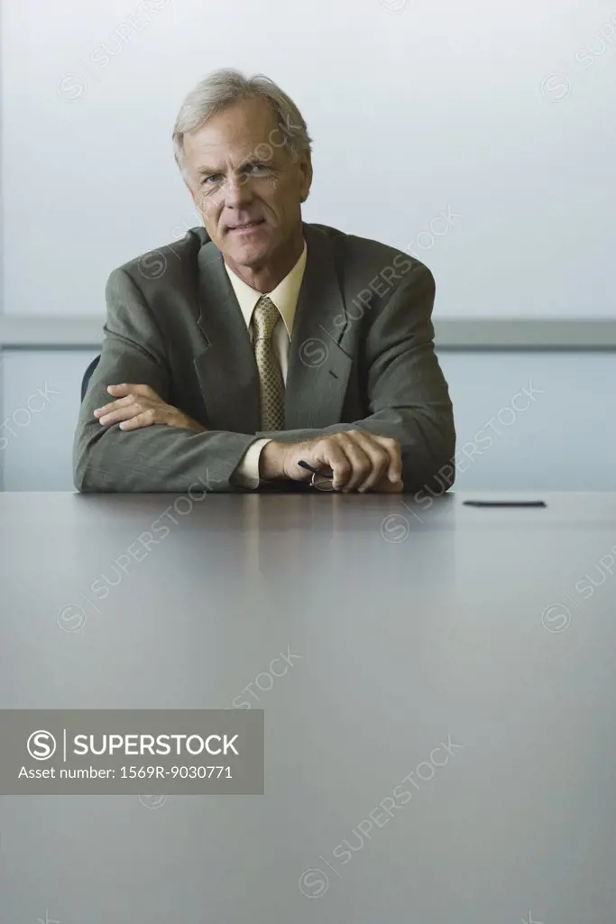 Businessman sitting with arms folded, looking at camera
