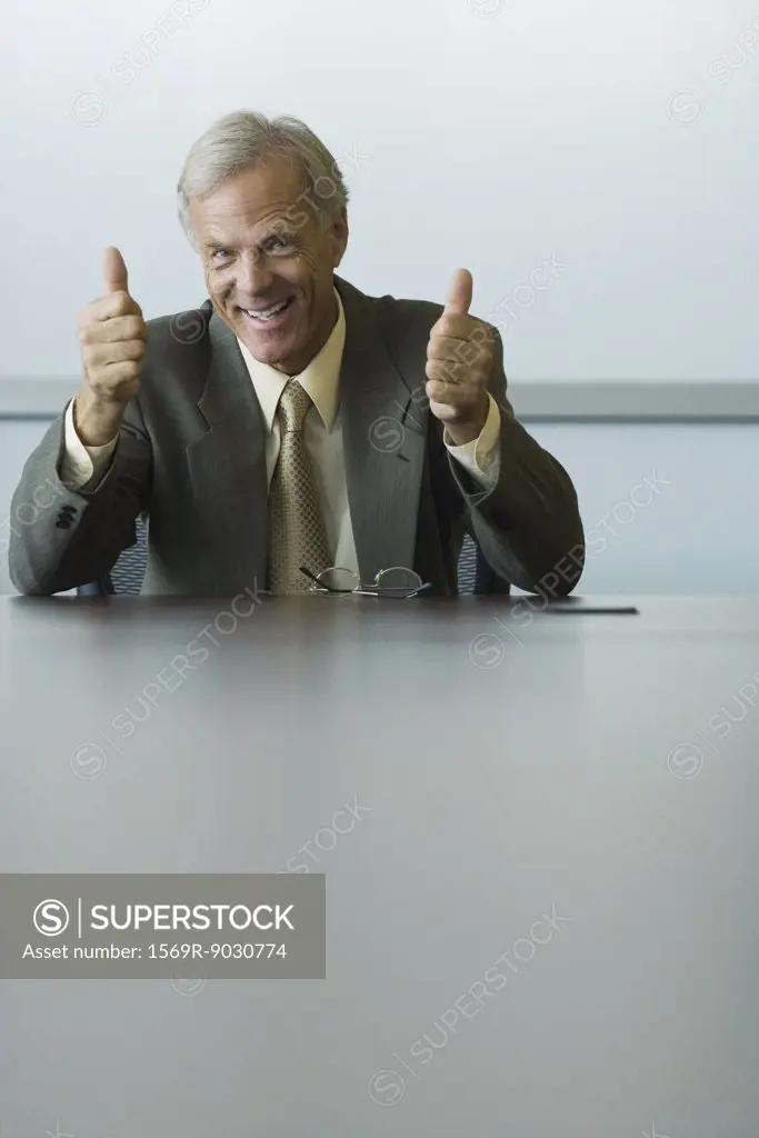 Businessman giving two thumbs up, smiling at camera