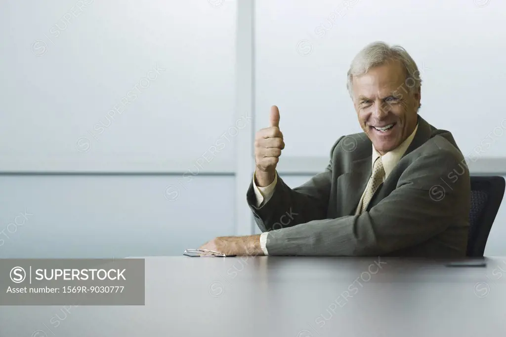 Businessman making thumbs up gesture and smiling at camera