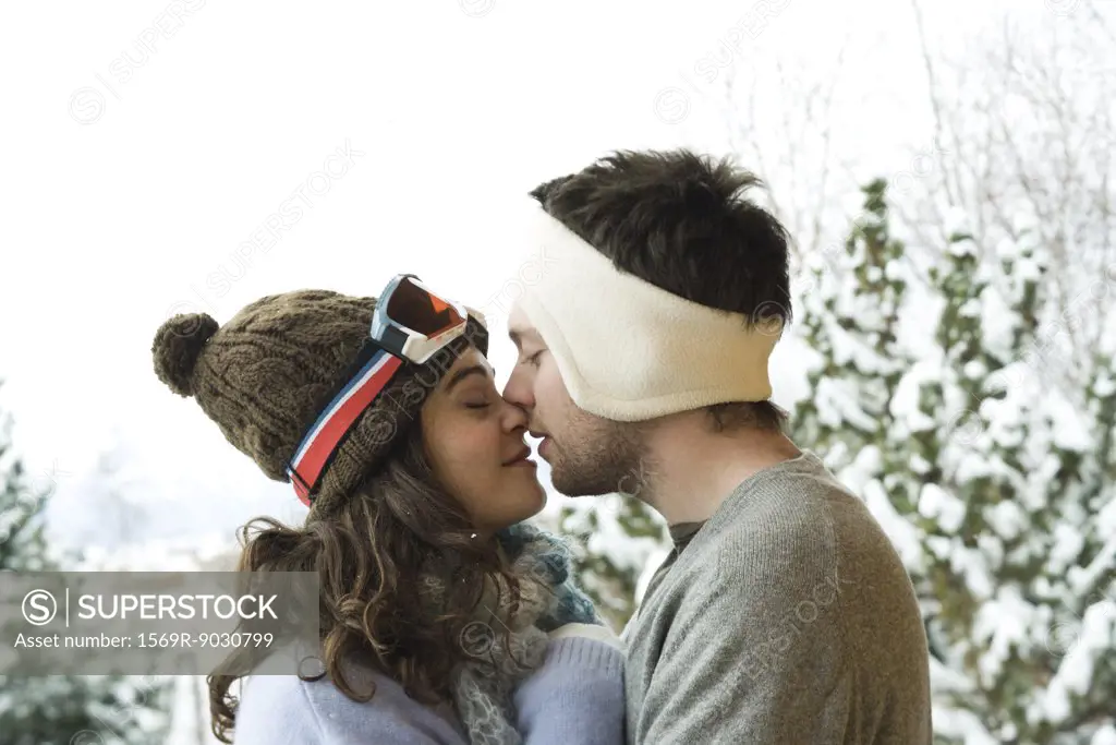 Young couple in winter clothes, kissing, side view