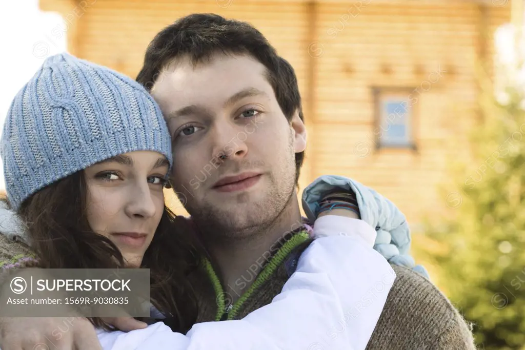 Teen girl and young man hugging, looking at camera, portrait