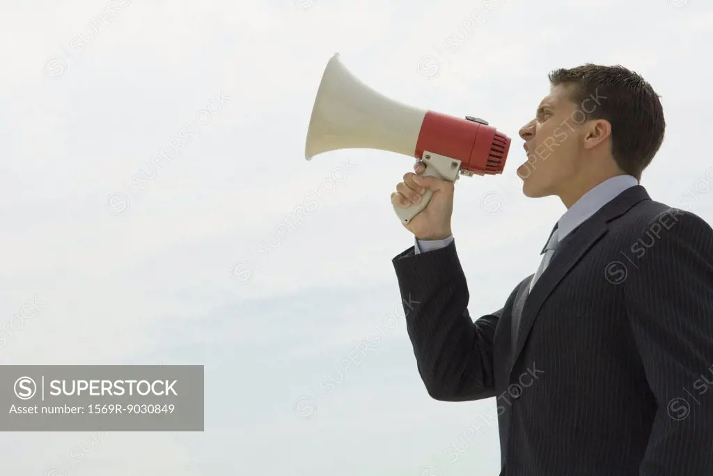 Young businessman shouting into megaphone, side view
