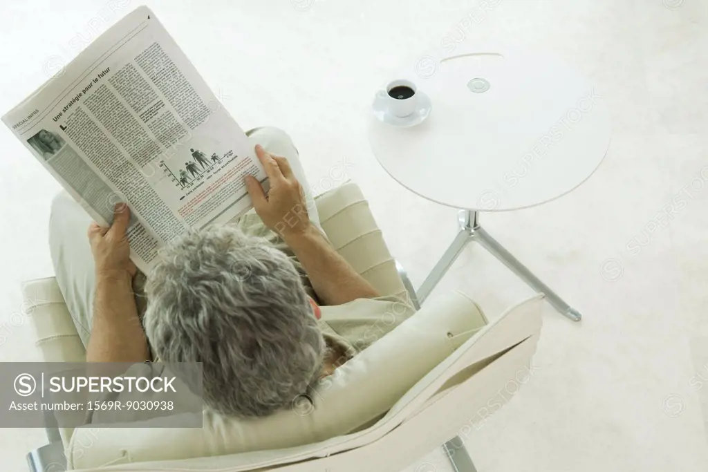 Man sitting, reading newspaper, high angle view
