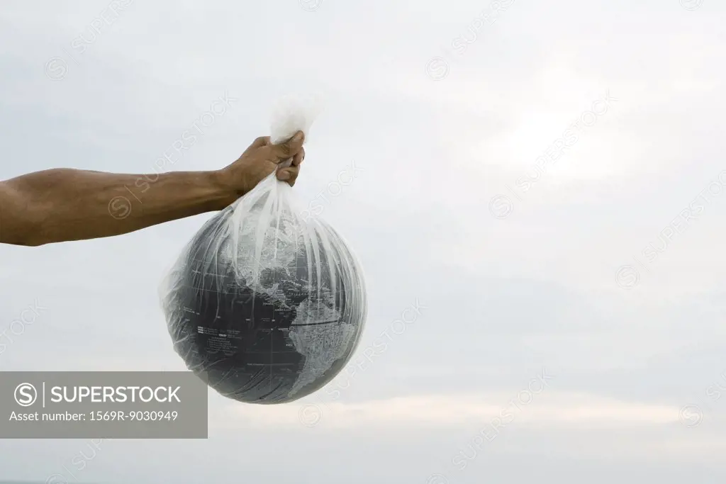 Cropped view of arm holding globe in plastic bag