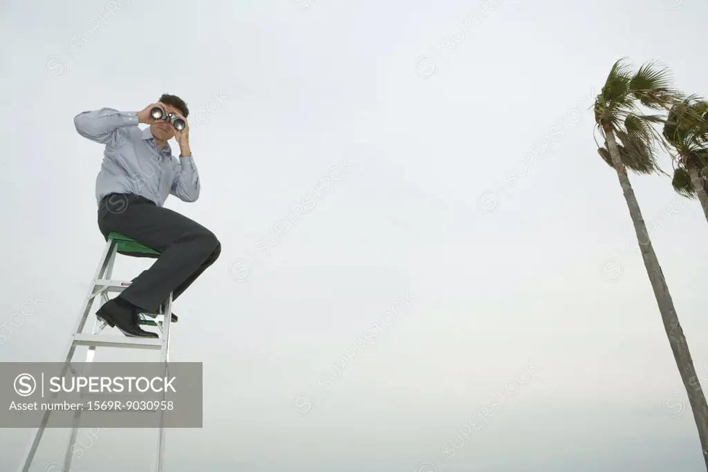 Man sitting on top of ladder looking through binoculars