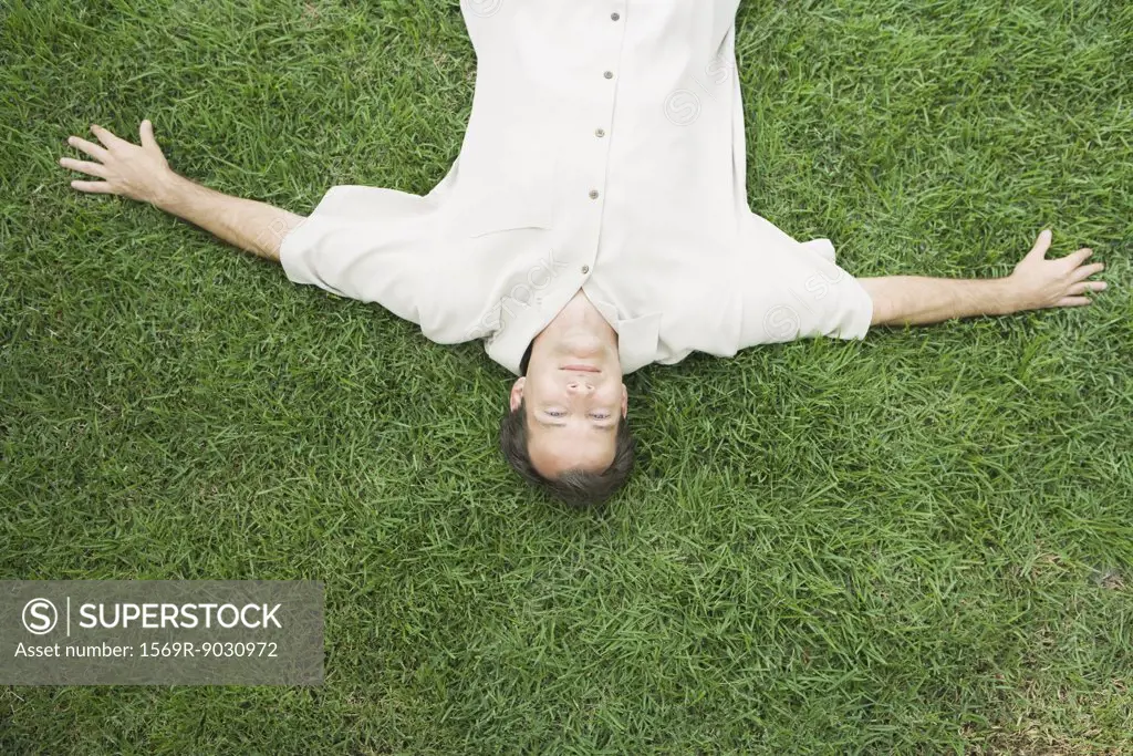 Man lying on back on grass, smiling at camera, viewed from directly above
