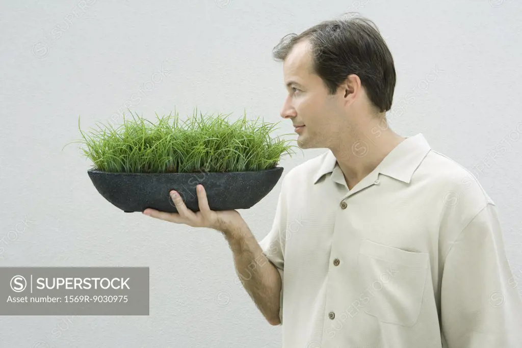 Man smelling bowl of grass, side view