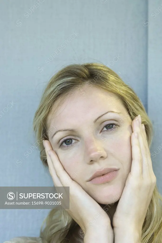 Woman holding face, looking at camera