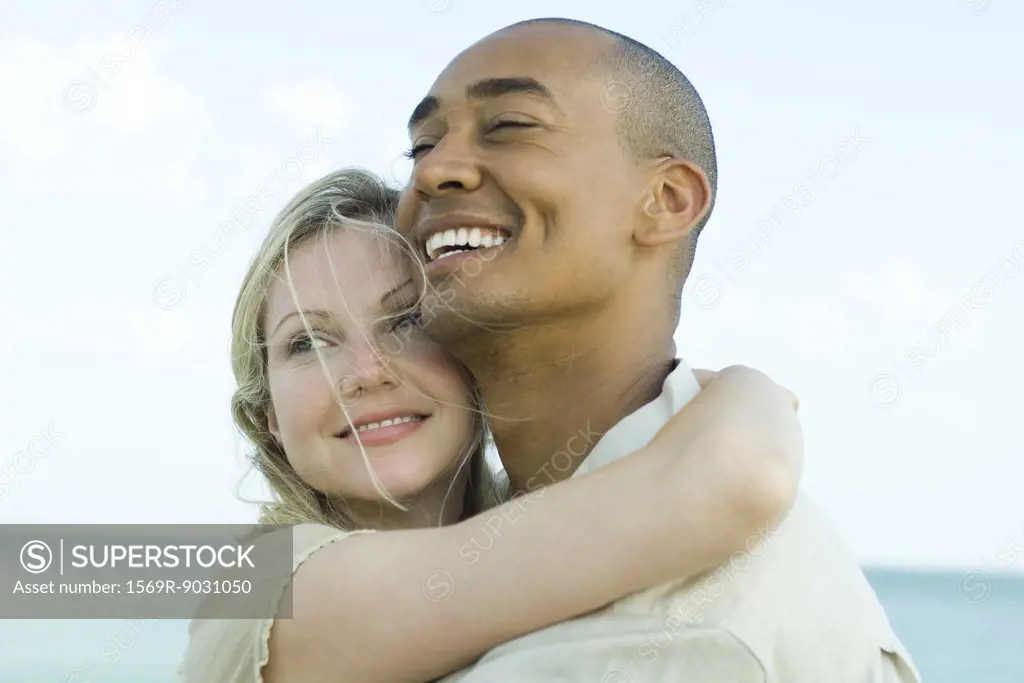 Couple embracing and smiling outdoors, close-up