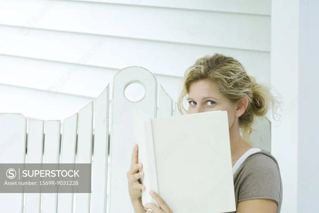 Woman looking over book at camera