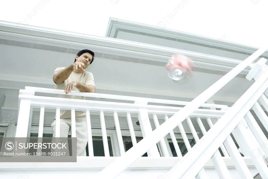 Man throwing drink can from deck, low angle view