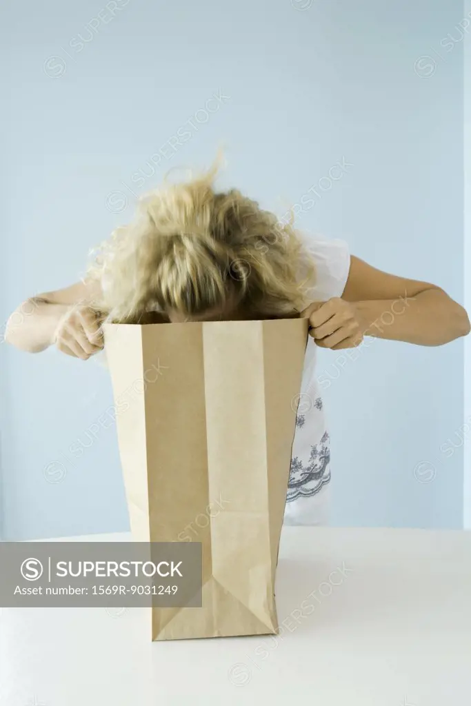 Woman leaning forward, looking into grocery bag