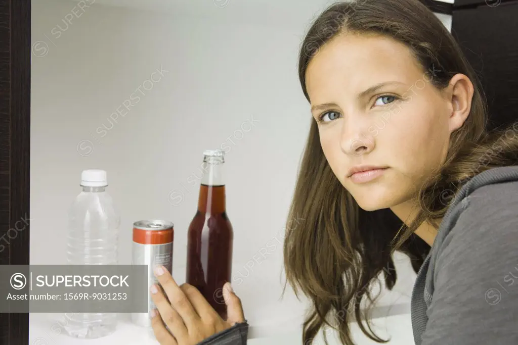 Teen girl next to variety of drinks, reaching for bottled soft drink