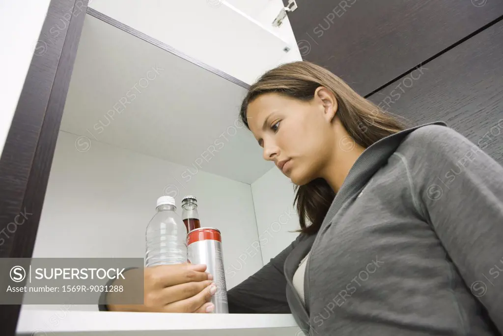 Teen girl standing with arm around various drinks, low angle view