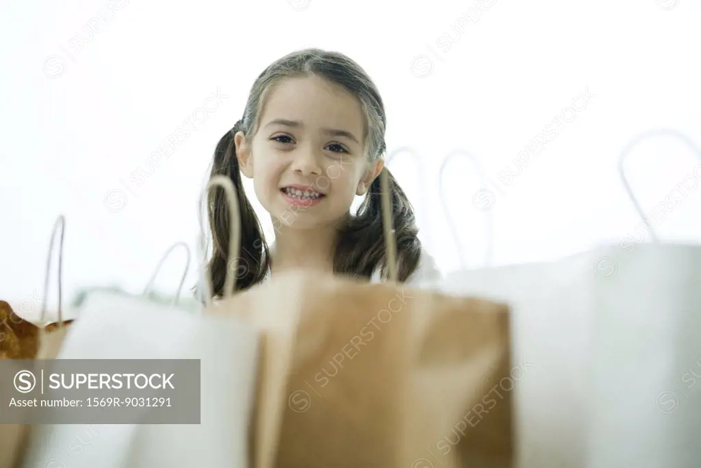Little girl smiling, shopping bags in foreground