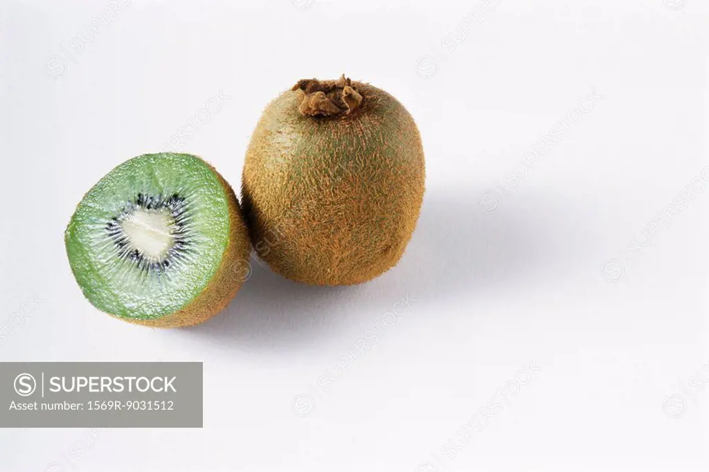 Two kiwis, one cut, the other whole, close-up