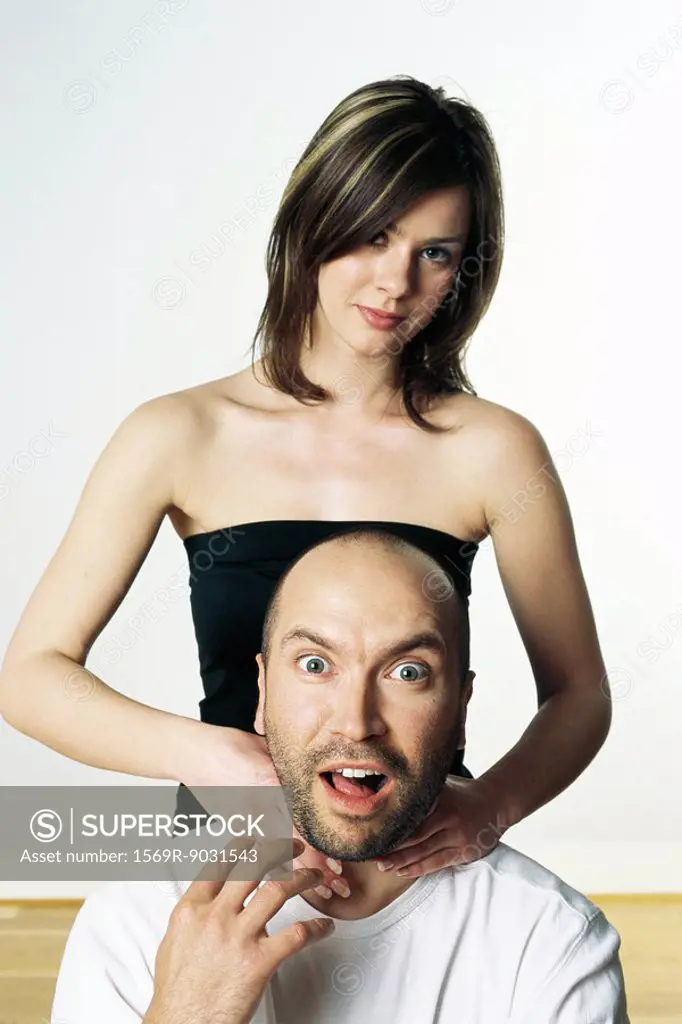 Woman pretending to strangle man, both looking at camera