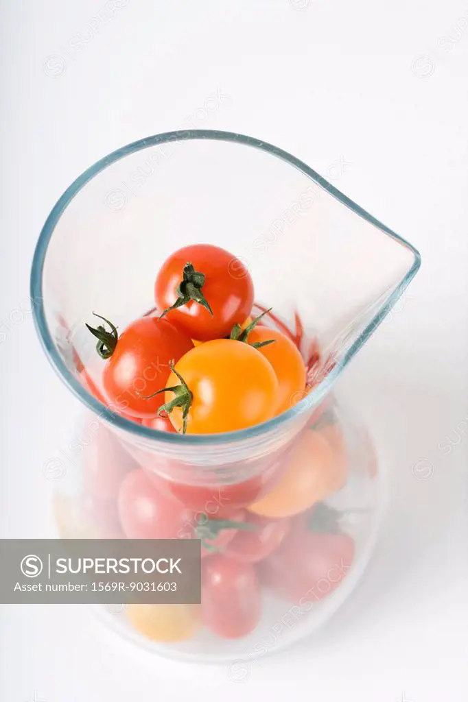 Red and yellow cherry tomatoes in pitcher, high angle view
