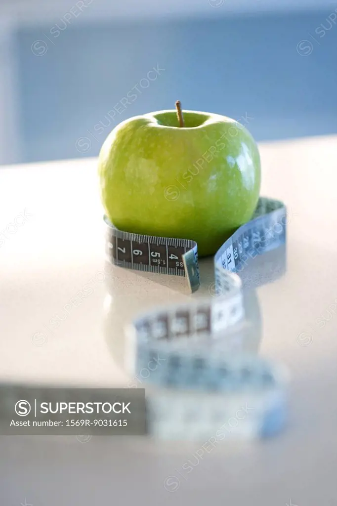 Green apple with tape measure around it, close-up