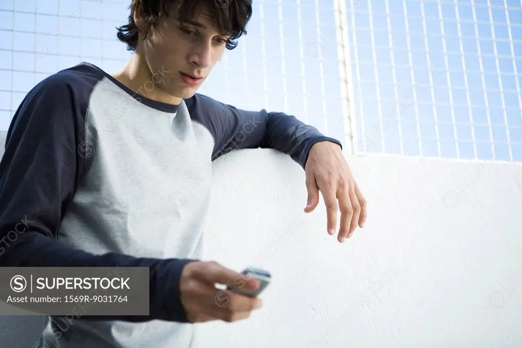 Young man looking down at cell phone, close-up