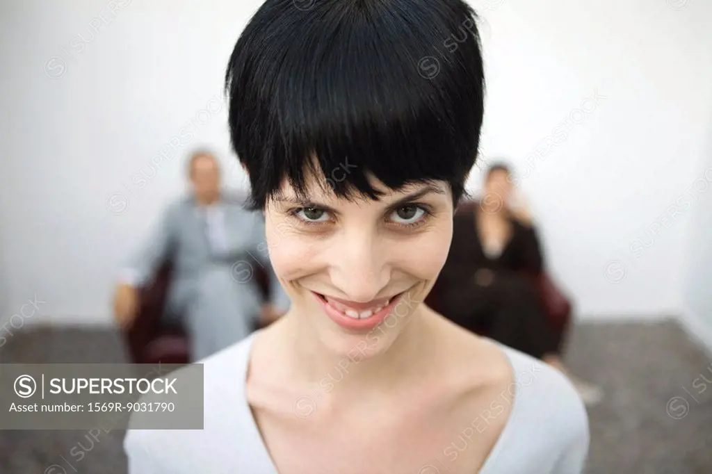 Woman smiling at camera, one eyebrow raised, close-up