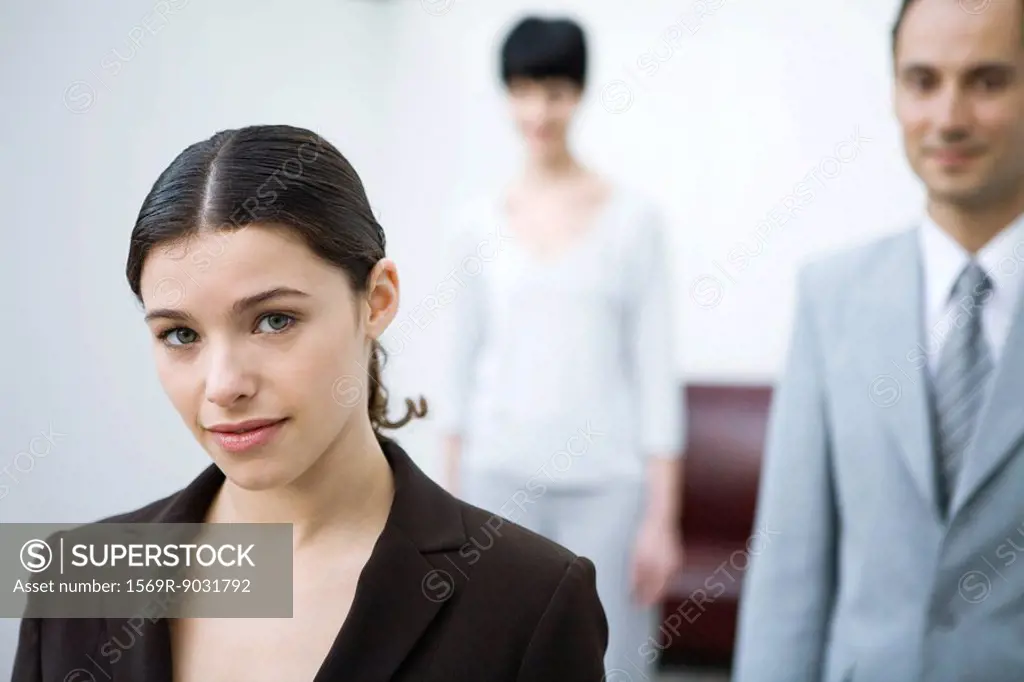Businesswoman smiling at camera, colleagues in background