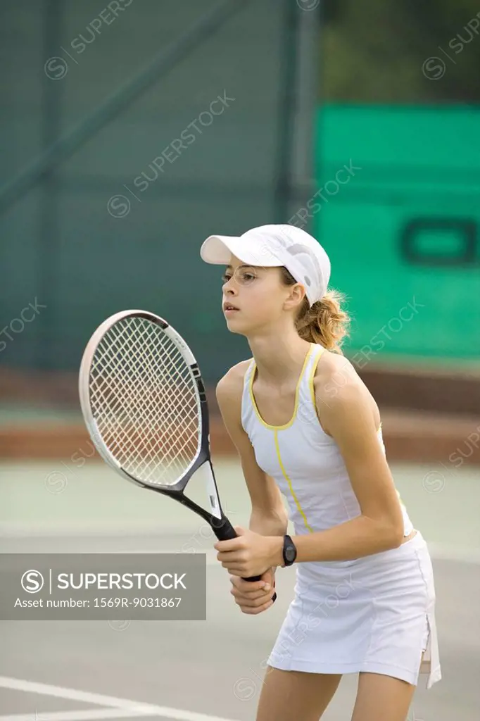 Teenage girl playing tennis, looking away