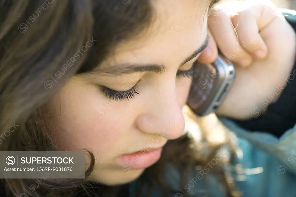 Teenage girl using cell phone, looking down, close-up