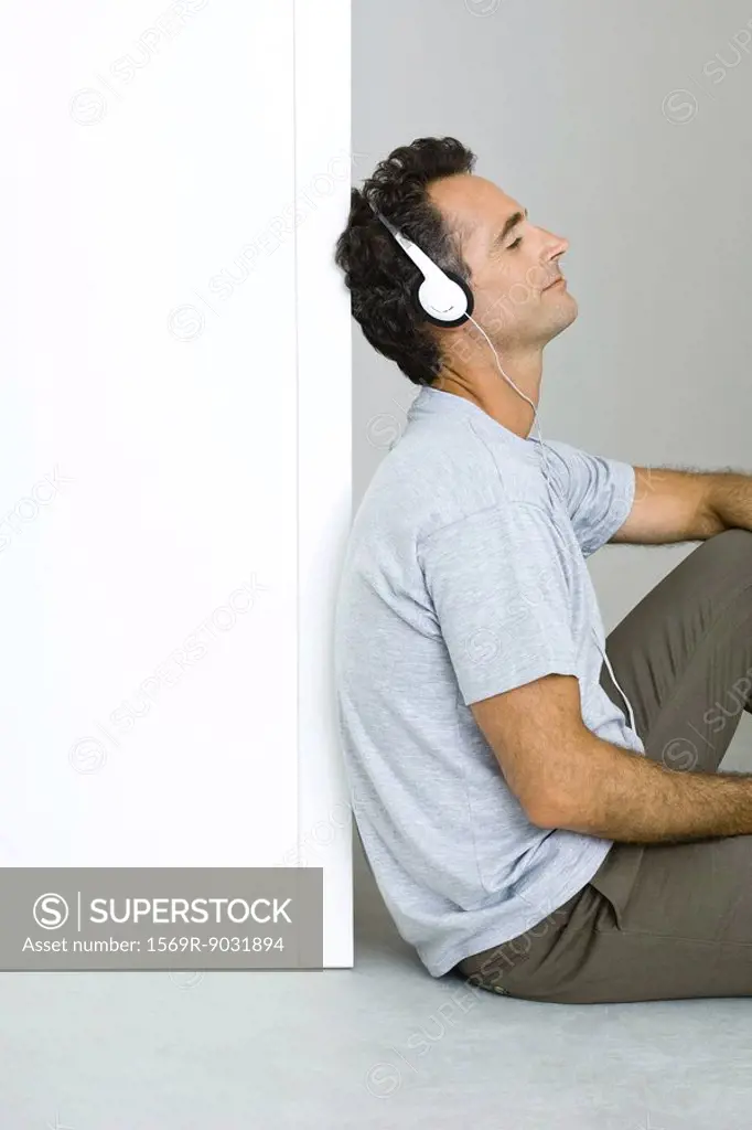 Man sitting on the ground, listening to headphones, eyes closed
