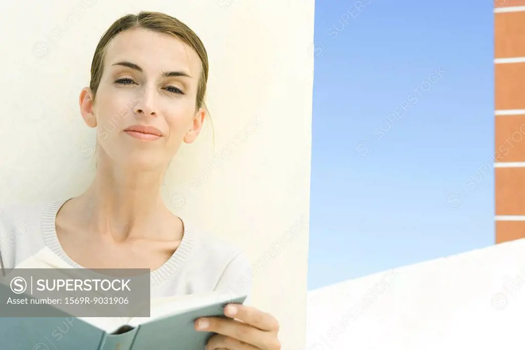 Woman holding book, smiling at camera