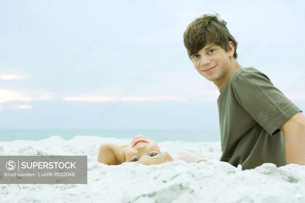 Two brothers at the beach, both smiling at camera