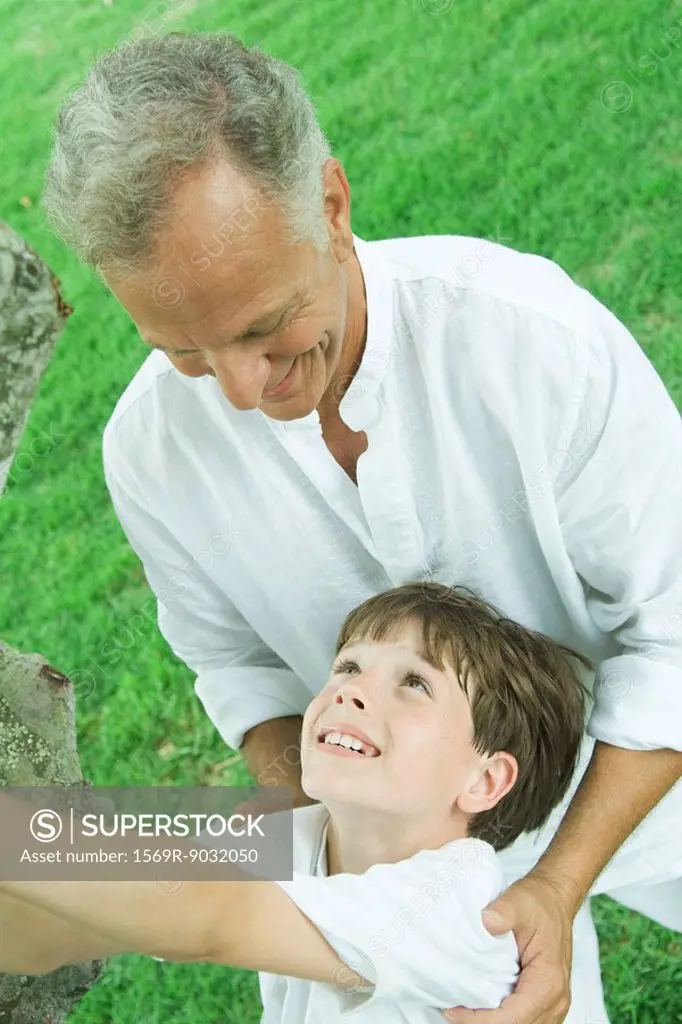 Grandfather and grandson outdoors together, smiling at each other, tilted high angle view