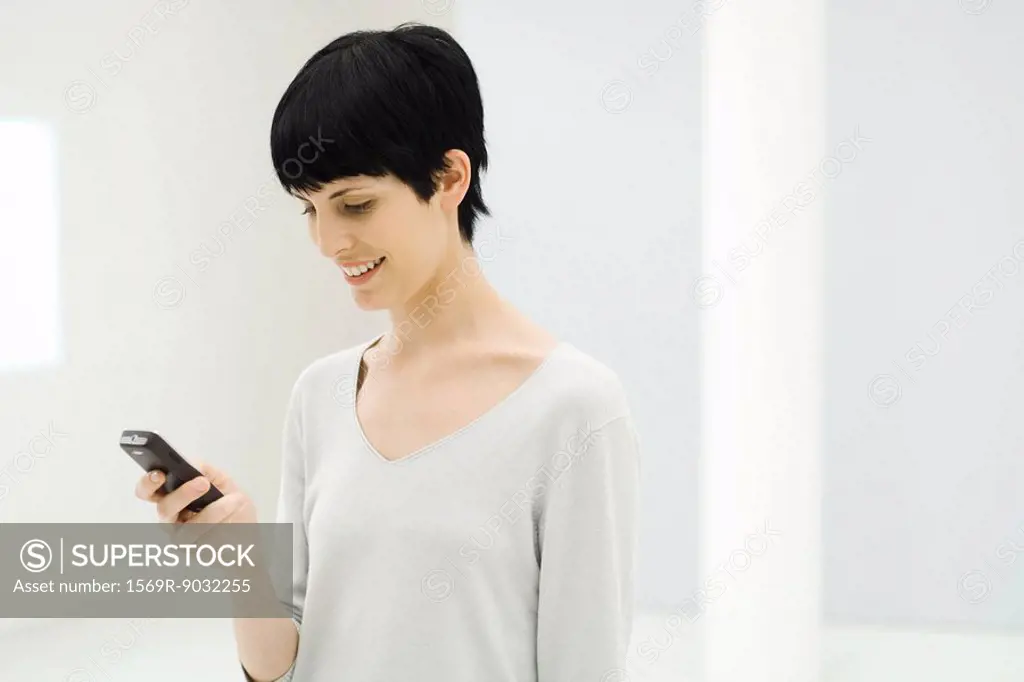 Woman looking down at cell phone, smiling