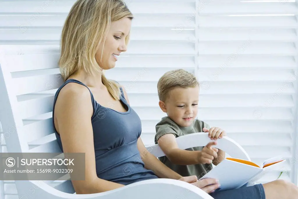 Mother and son reading book together, both smiling