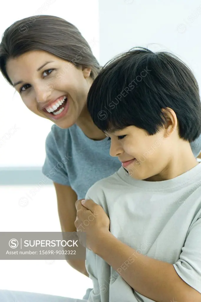 Teenage girl looking over boy´s shoulder at camera, both smiling